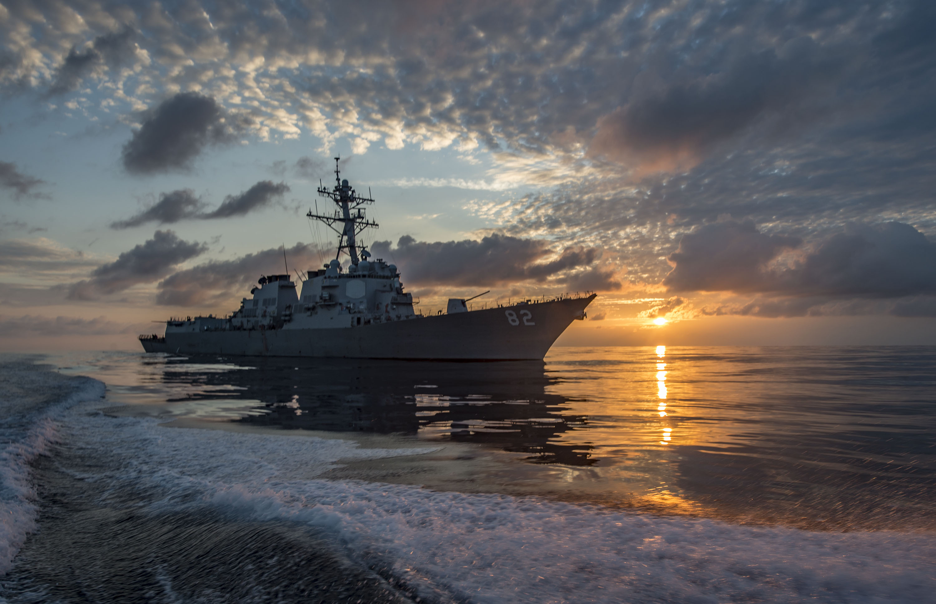 A U.S. Navy Arleigh Burke-class guided-missile destroyer underway at sunrise